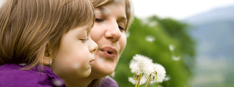 grandmother and grandson blowing dandelion seeds